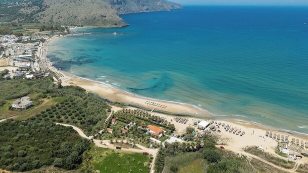 An aerial view of a coastal area with a beach, a small town, and a mountain in the background. - La Palma Beachfront Suites (Apokoronas)