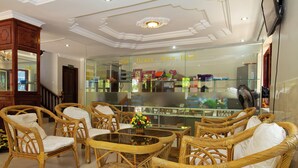 A lobby with wicker furniture, a glass display case, and a ceiling with decorative molding. - Damnak Riverside Villa (Siem Reap)