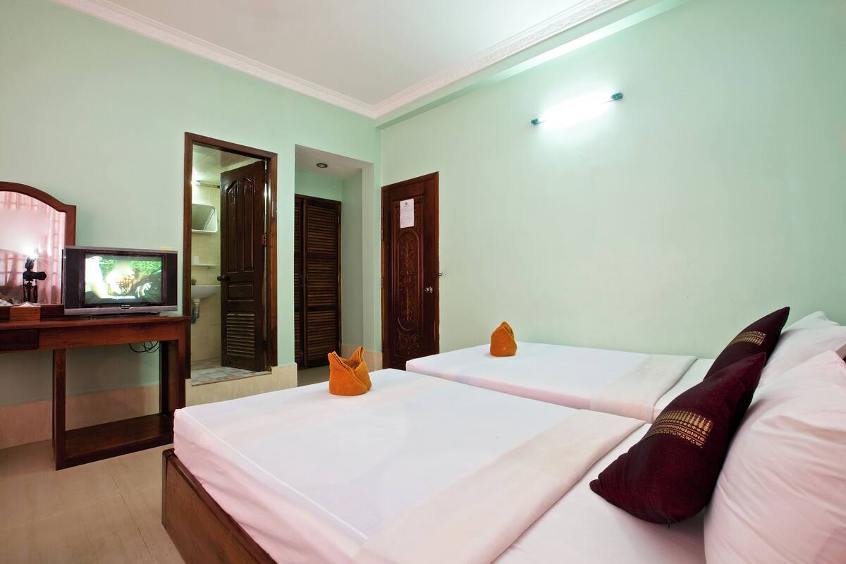A hotel room with two beds, a TV, a desk, and a mirror.