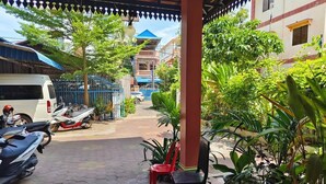 A covered outdoor area with a tiled floor, potted plants, and a few chairs. - Damnak Riverside Villa (Siem Reap)