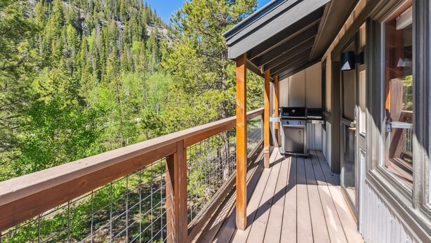 A wooden deck with a kitchen area, overlooking a forested mountain. - HotTub, Grill | Main St-Shops, Lake (Frisco)