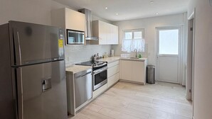 A modern kitchen with stainless steel appliances, white cabinetry, and a tiled backsplash. - Sunset Bliss Suite at Commandeurs (Oranjestad)