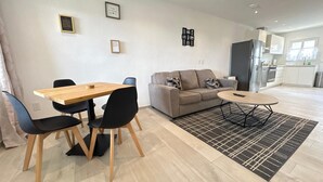 A modern living room with a wooden dining table, black chairs, a grey sofa, and a black and white rug. - Sunset Bliss Suite at Commandeurs (Oranjestad)