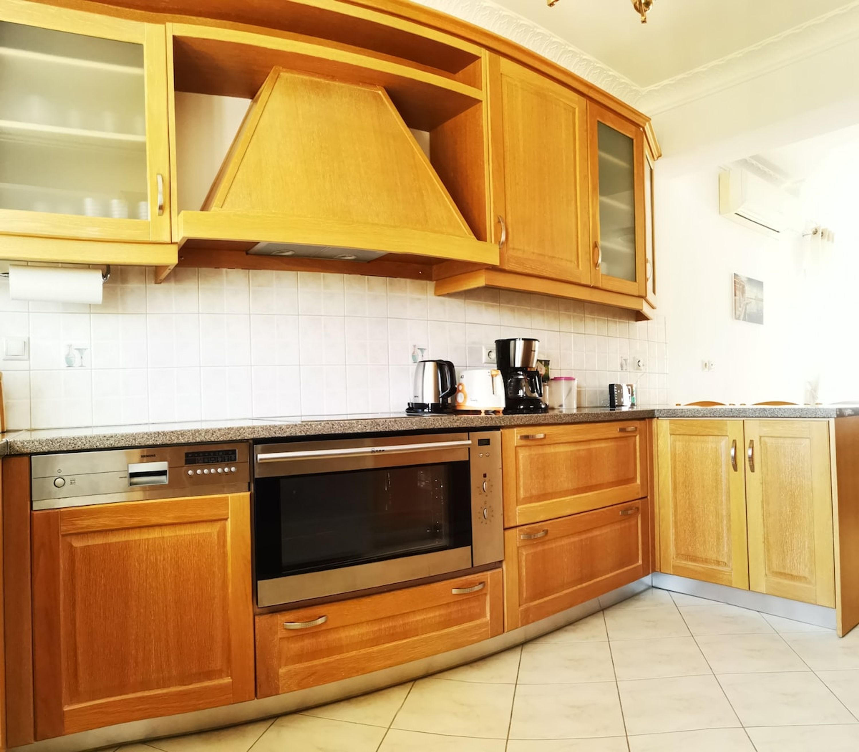 A kitchen with wooden cabinets, a built-in oven, a dishwasher, and a coffee maker.