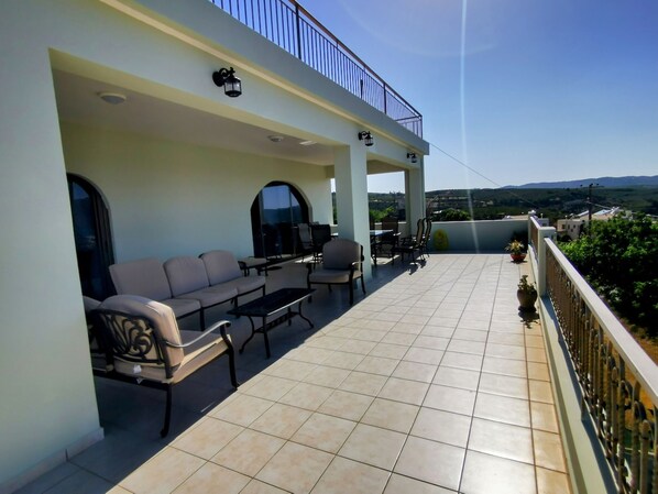 A covered outdoor seating area with a sofa, chairs, and a table.