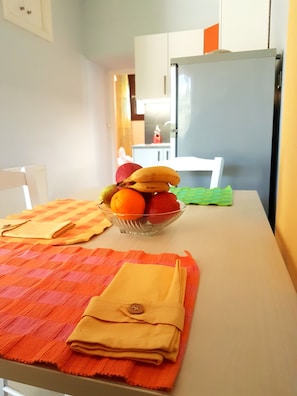 A dining table with a fruit bowl, a folded tablecloth, and a chair. - Elia Guesthouse - Kissamos (Kissamos)
