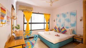 A bedroom with a bed, a desk, a chair, a ceiling fan, and a window with curtains. - goSTOPS Bengaluru Gandhi Nagar Majestic. (Bengaluru)