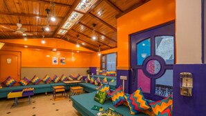 A room with multiple seating areas, wooden ceiling, and a large window with a view. - goSTOPS Bengaluru Gandhi Nagar Majestic. (Bengaluru)