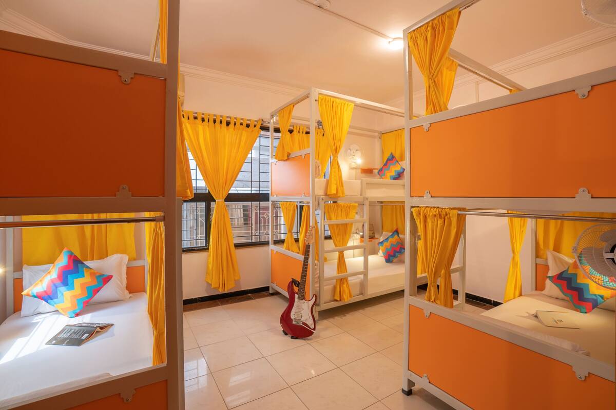 A room with bunk beds, yellow curtains, and a guitar on the floor.