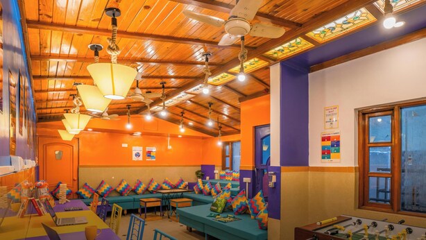 A vibrant room with wooden ceilings, colorful seating, and a foosball table. - goSTOPS Bengaluru Gandhi Nagar Majestic. (Bengaluru)