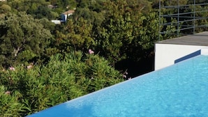 En swimmingpool med utsikt över havet och ett fartyg i fjärran.
