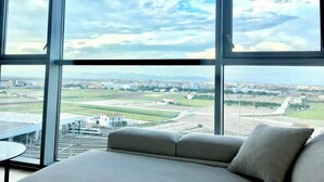 A room with a large window offering a view of a cityscape and airport.