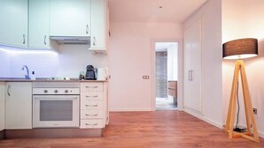 A modern kitchen with white cabinets, a built-in oven, and a coffee maker. There is a wooden floor and a lamp in the corner. - Next to the Silk Exchange and Central Market (Valencia)
