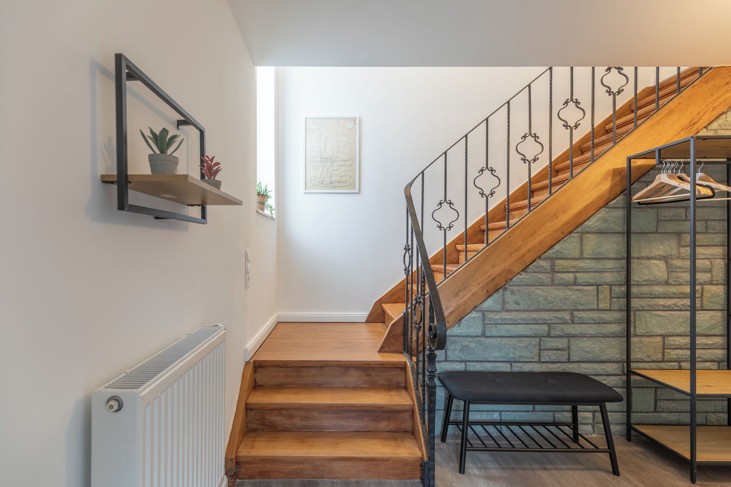 Una escalera de madera con barandillas de metal que conduce a un muro de piedra.