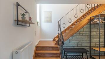 Una escalera de madera con barandillas de metal que conduce a un muro de piedra.