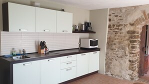 Una cocina con alacenas blancas, un microondas y una cafetera sobre la encimera.