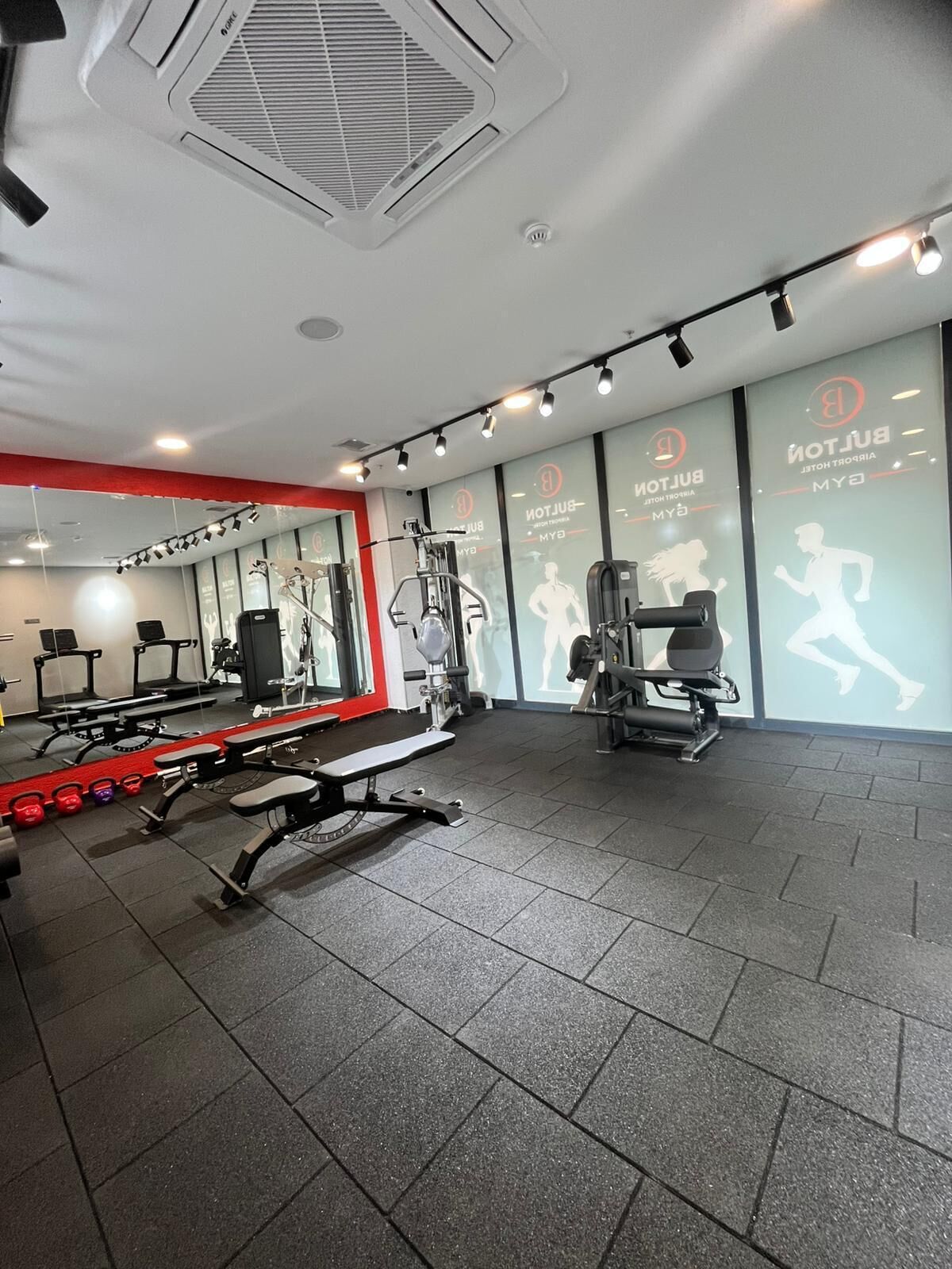 A gym with exercise equipment, a bench, and a wall with motivational text.