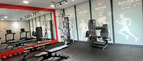 A gym with exercise equipment, a bench, and a wall with motivational text.