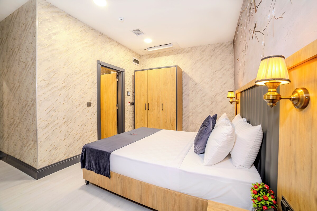 A modern bedroom with a wooden bed, a nightstand, a wardrobe, and a wall-mounted lamp.