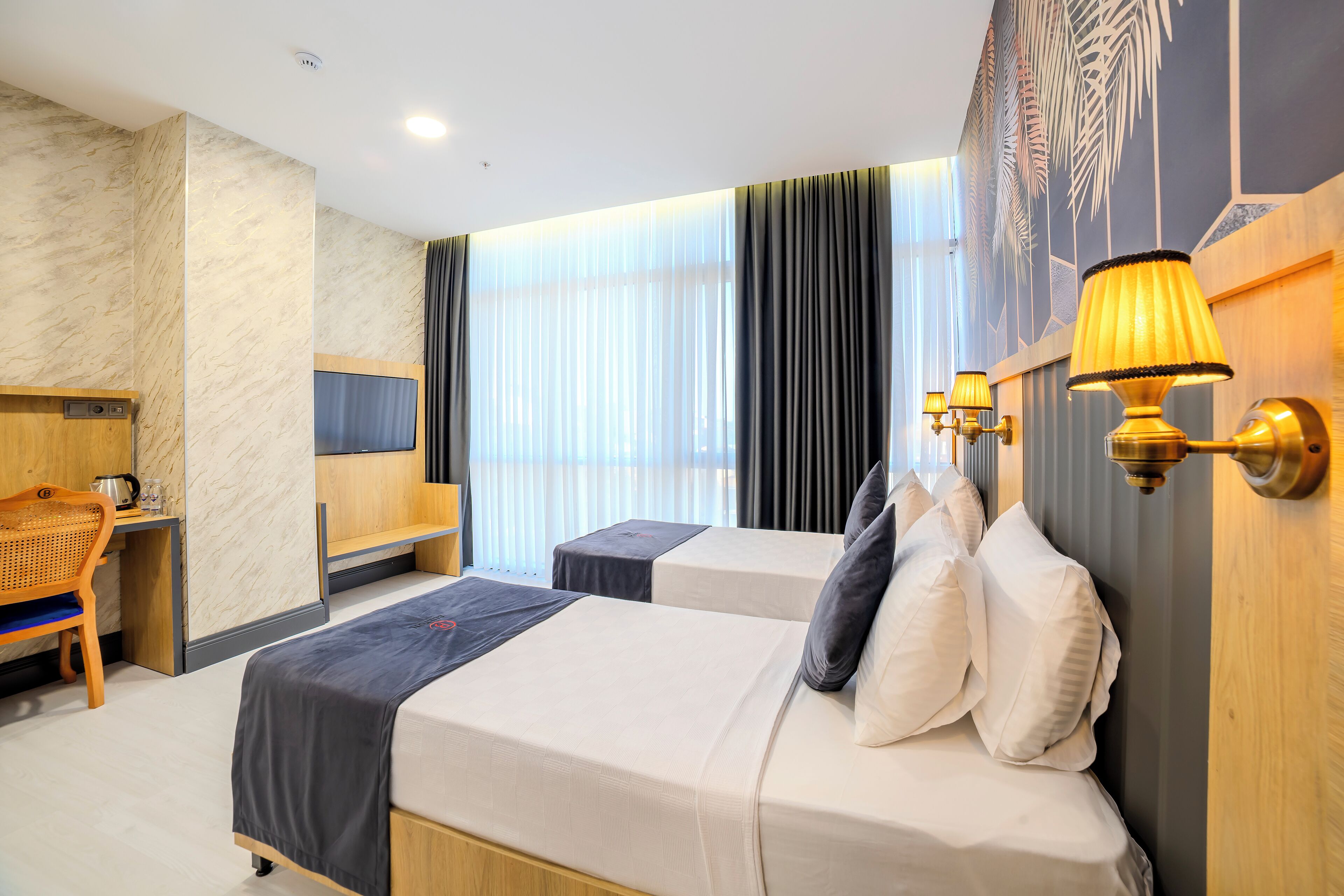 A hotel room with two beds, a desk, and a chair.