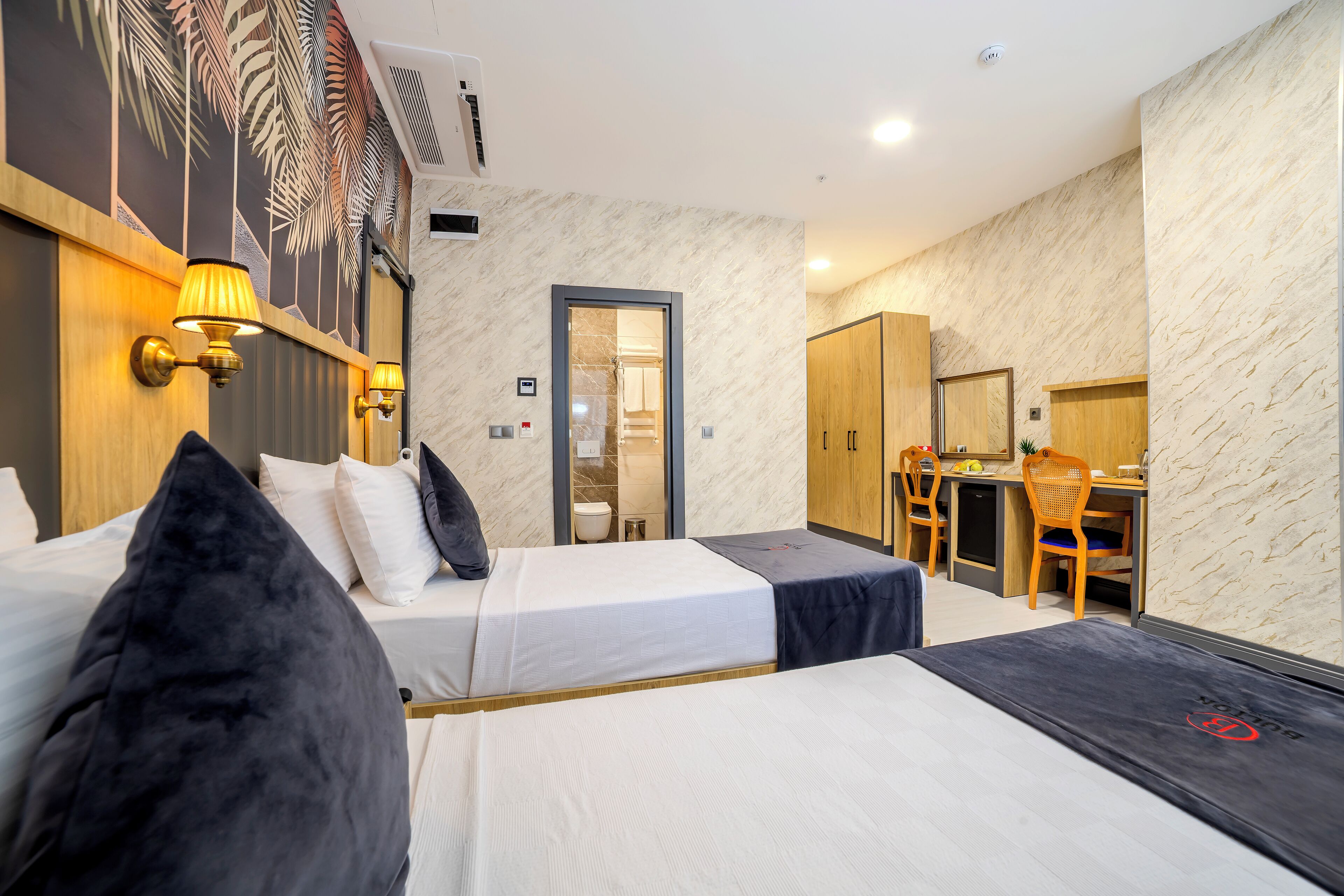 A hotel room with two beds, a desk, and a chair.