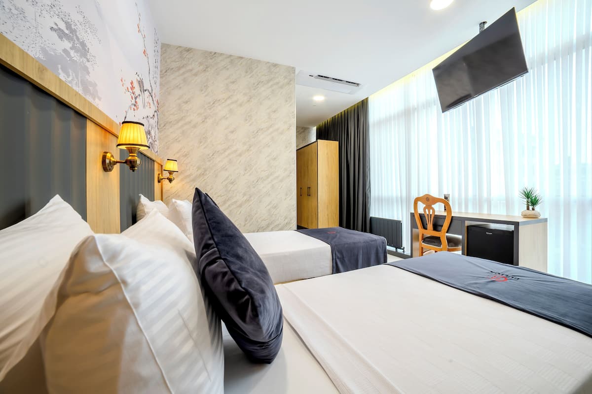 Ein Hotelzimmer mit zwei Betten, einem Schreibtisch, einem Stuhl und einem Fernseher.