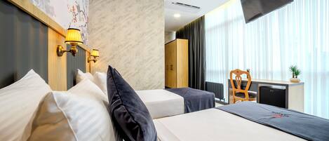 Habitación de hotel con dos camas, un escritorio, una silla y un televisor.