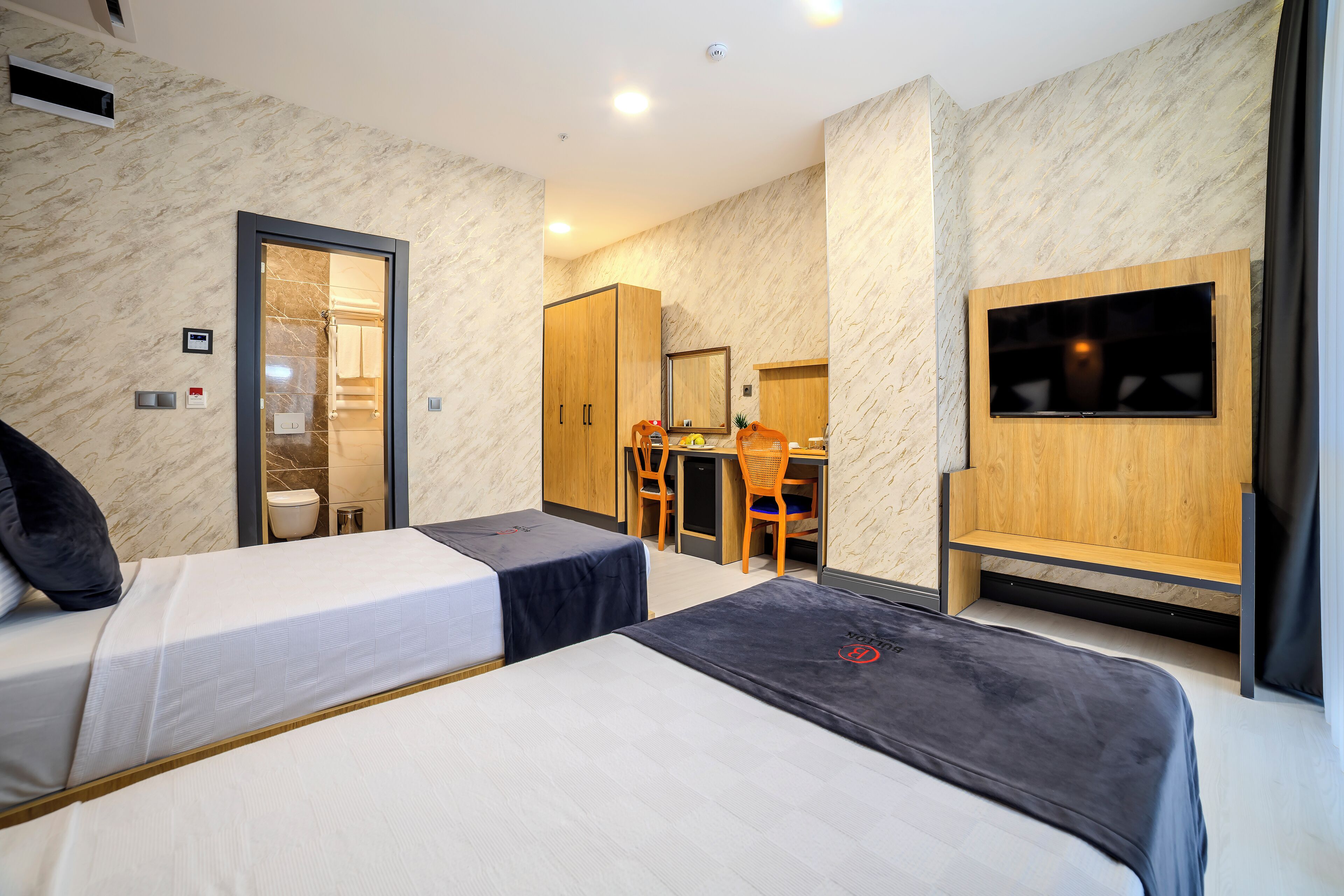 Una habitación de hotel con dos camas, un escritorio, una silla, un televisor y un armario.