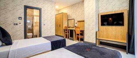 Una habitación de hotel con dos camas, un escritorio, una silla, un televisor y un armario.