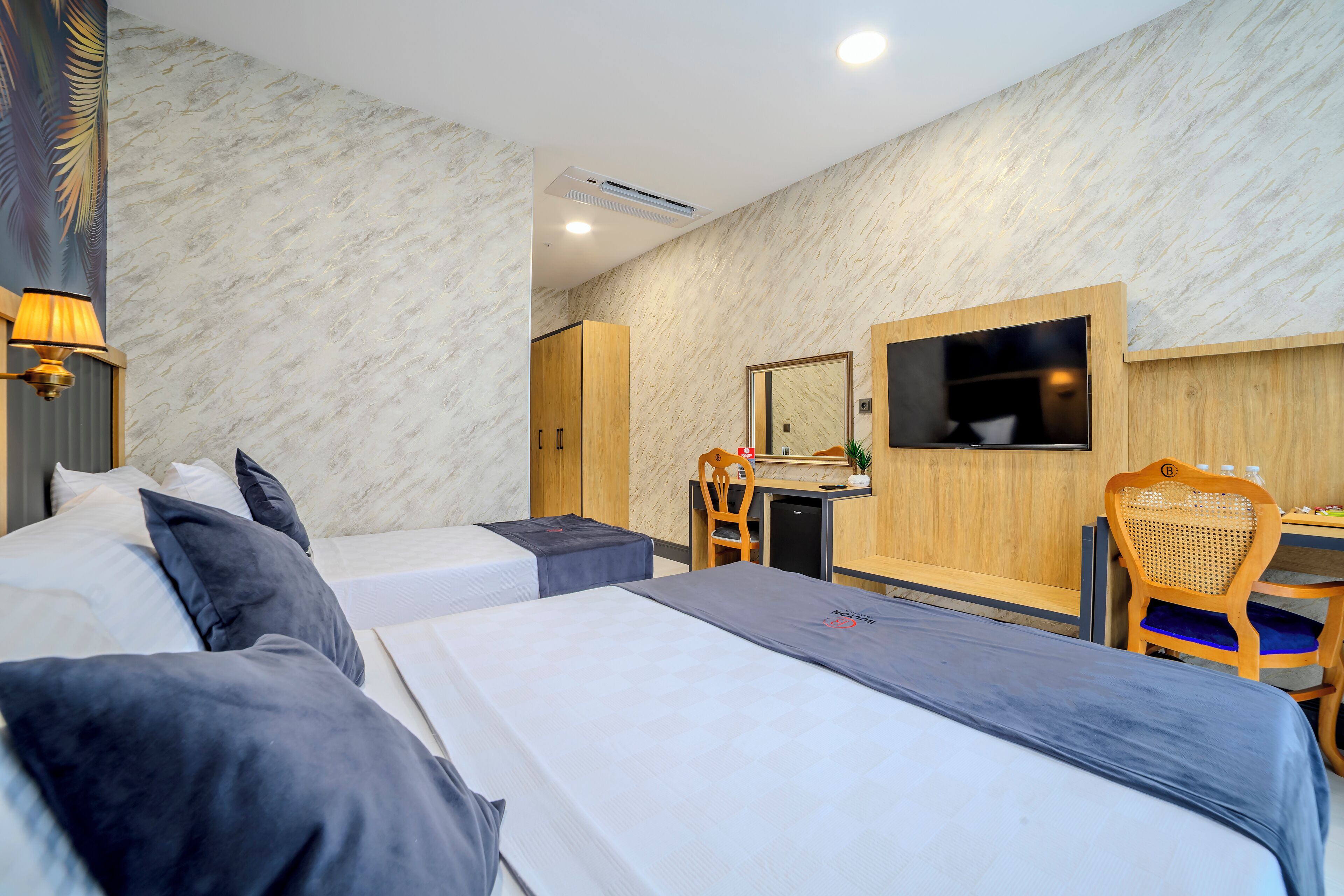 Une chambre d’hôtel avec deux lits, un bureau, une chaise, une télévision et un miroir.