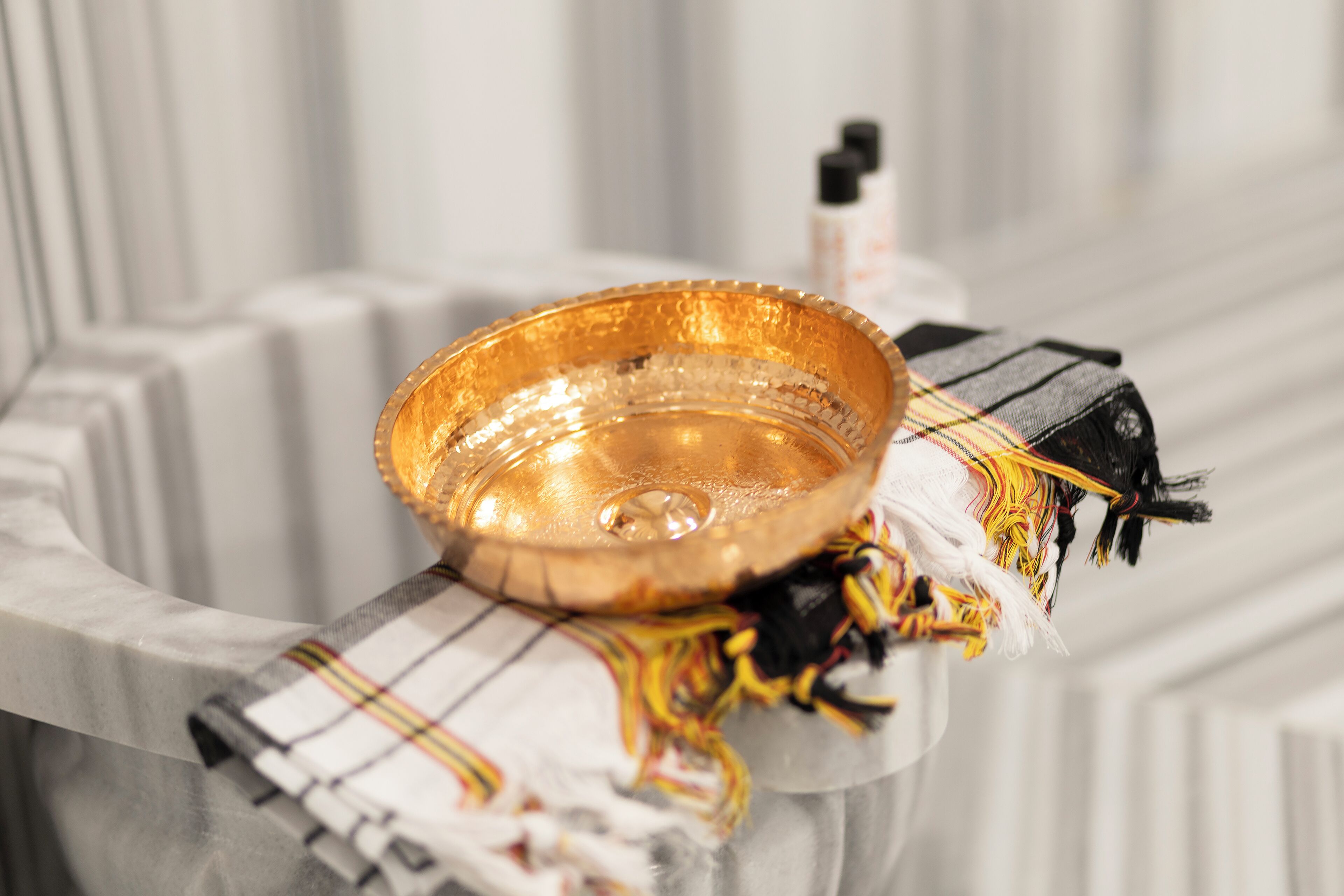 Een gouden dienblad op een witte marmeren oppervlak met een geruit kleed.