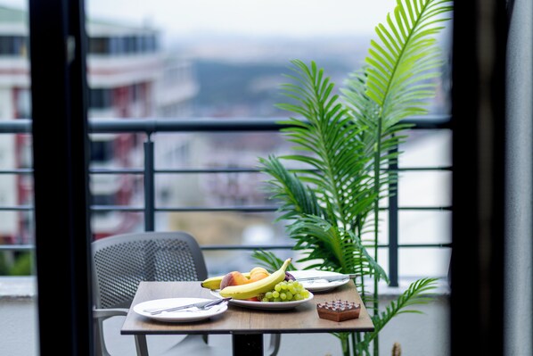 Mesa de jantar com pratos de fruta, uma cadeira e um vaso de planta.