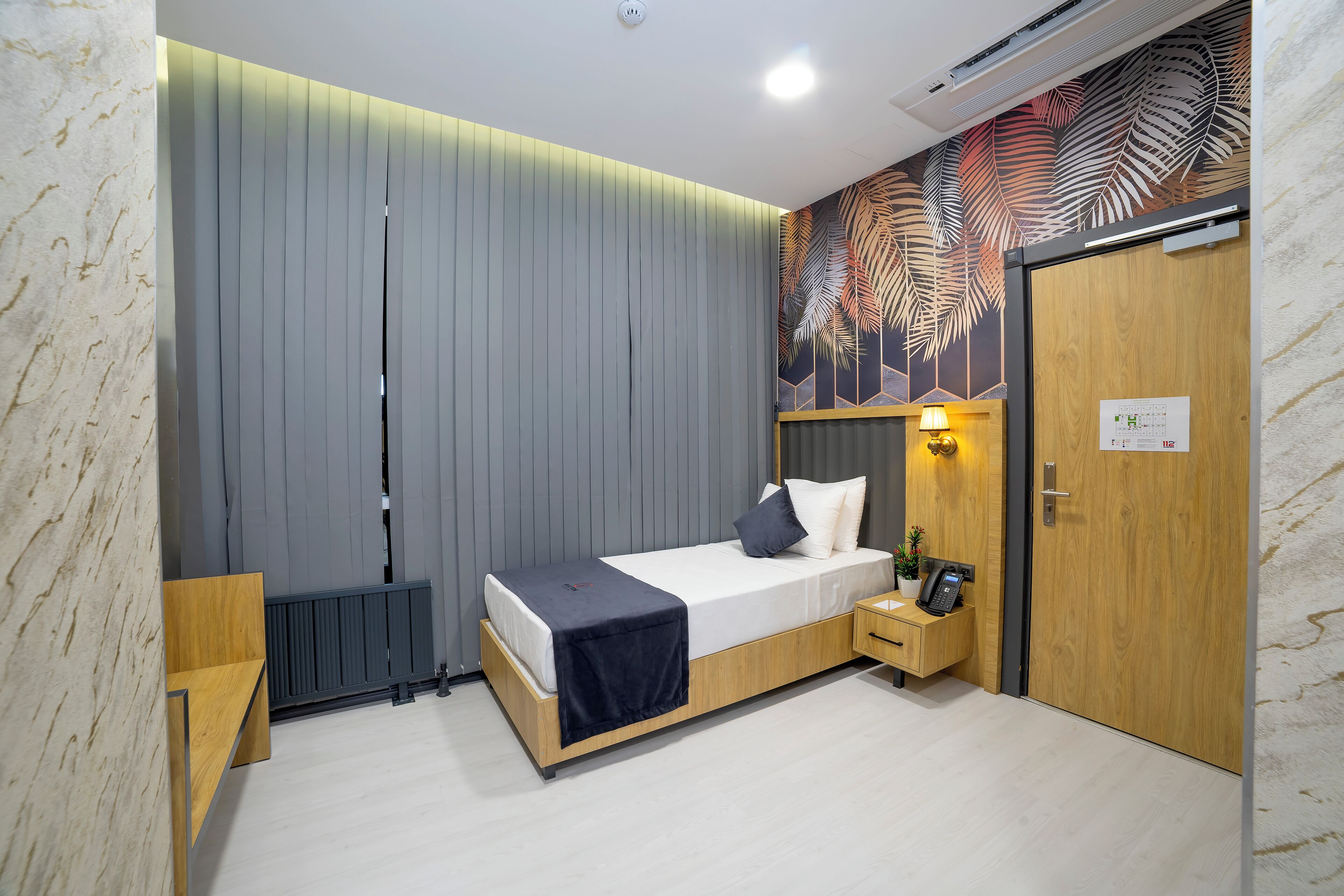 A modern bedroom with a bed, bedside table, and a wall-mounted lamp.