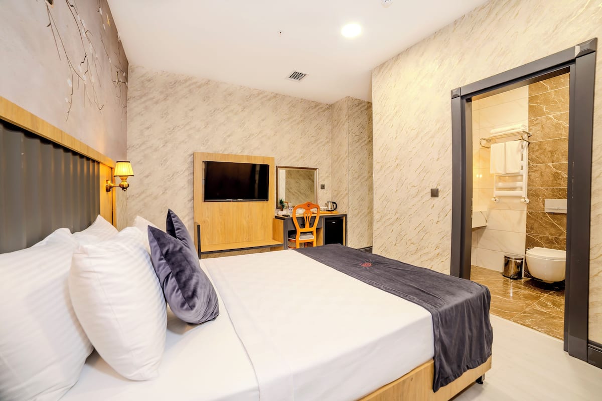 Ein Hotelzimmer mit Bett, Schreibtisch, Stuhl, Spiegel und einem Badezimmer mit Toilette und Waschbecken.