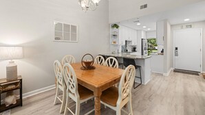 Una cocina moderna con armarios blancos, una mesa de comedor de madera y una araña.
