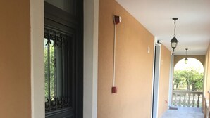 Un pasillo con una puerta negra, paredes color beige y piso de baldosas.