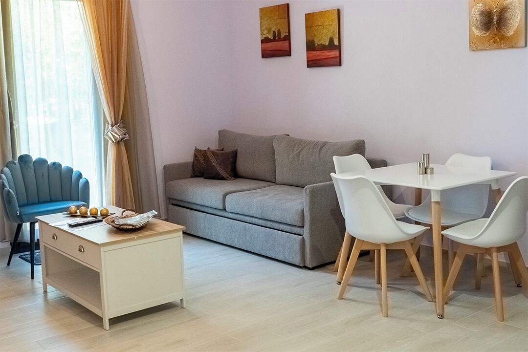 Una sala de estar moderna con un sofá, una mesa de comedor con sillas, una mesita auxiliar y un sillón azul.