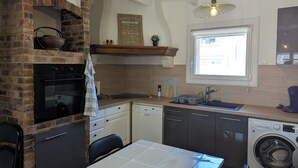 Een compacte keuken met een bakoven, een vaatwasser, een wasmachine en een raam voor natuurlijk licht.