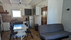 Een kleine keuken met een eettafel, stoelen, een bank en een wasmachine.