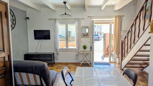 Een kamer met een bed, een televisie, een tafel en uitzicht op de straat.