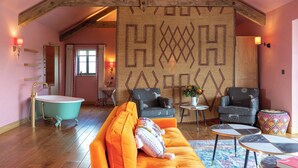 Une pièce chaleureuse avec une baignoire, un canapé, deux fauteuils et un mur décoré de motifs.