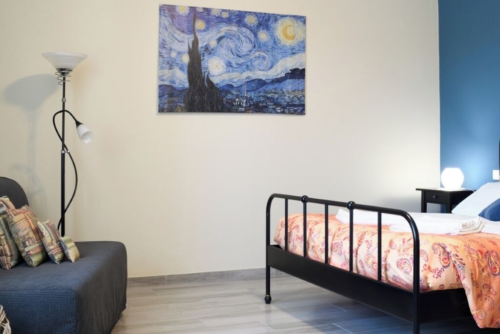 Ein Schlafzimmer mit einem Bett, einem Nachttisch, einer Lampe und einem Bild an der Wand.