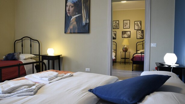 Una habitación de hotel con cama, escritorio, silla, lámpara y un cuadro en la pared.