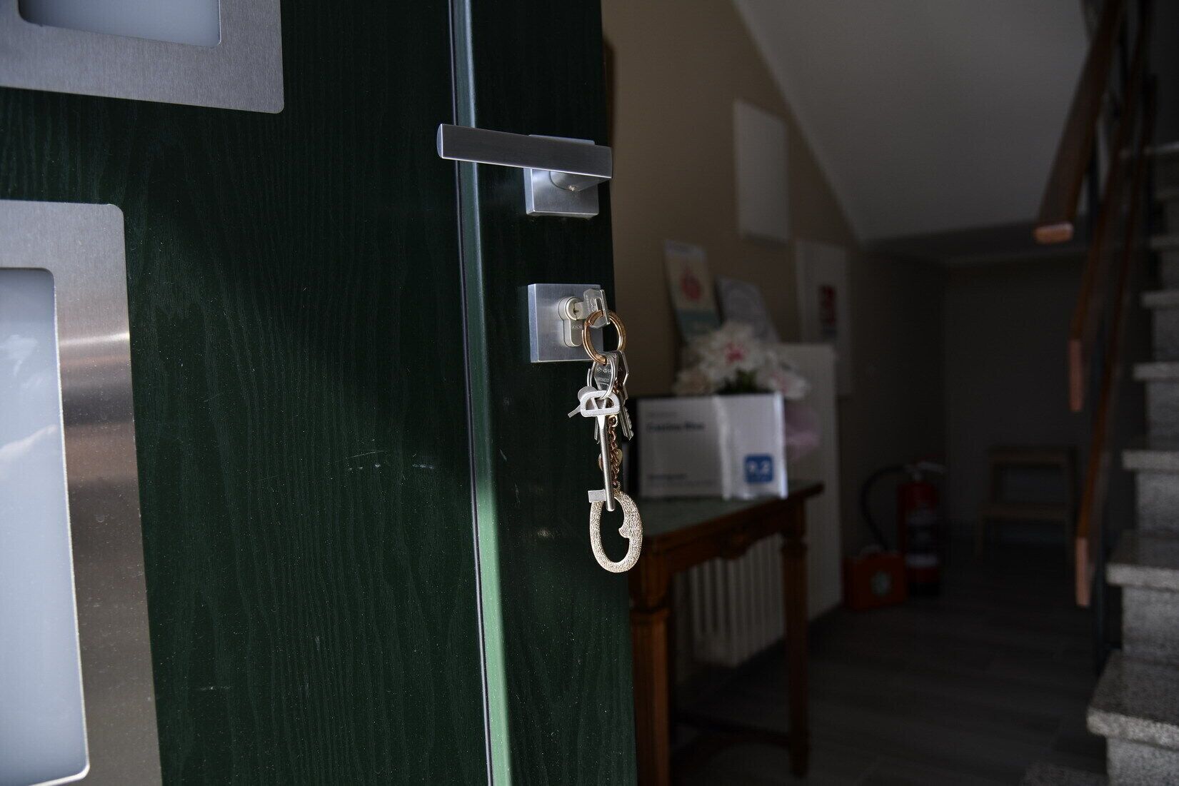 A dark green door with a silver handle and a key lock.