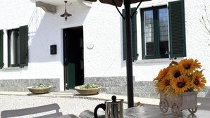 Una mesa con un libro, una cafetera y un jarrón de girasoles.