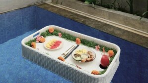 A dining table with food and drinks by a poolside. - ME Villas Pererenan (Canggu)