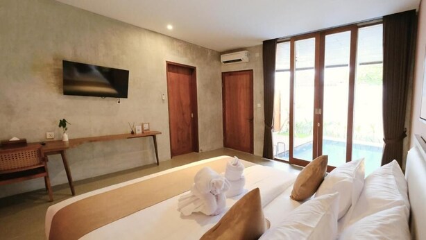 A hotel room with a large bed, a flat-screen TV mounted on the wall, a desk with a chair, and a sliding glass door leading to a balcony. - ME Villas Pererenan (Canggu)