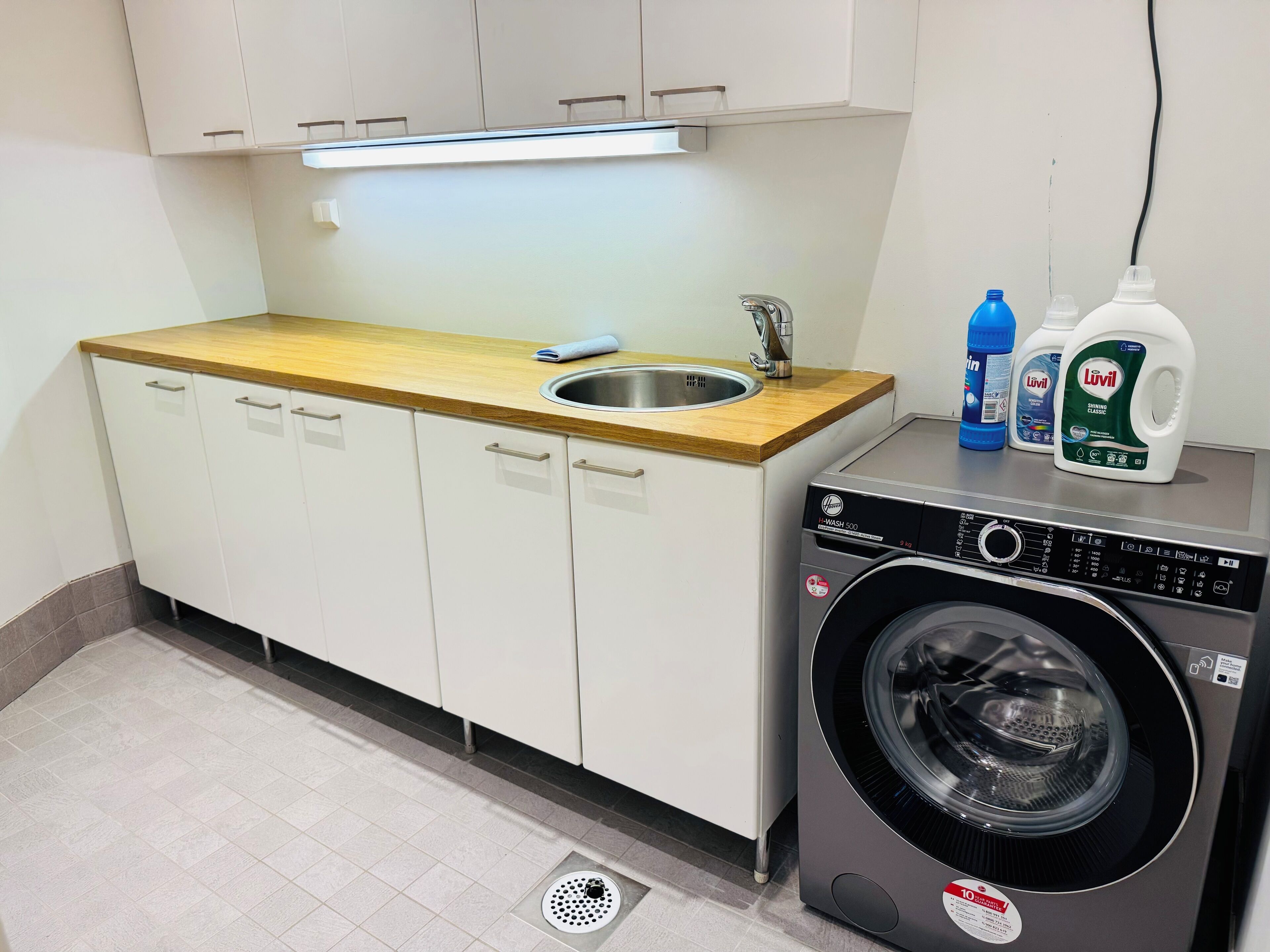 Een kleine keuken met een spoelbak, een houten aanrechtblad en een voorlader wasmachine.