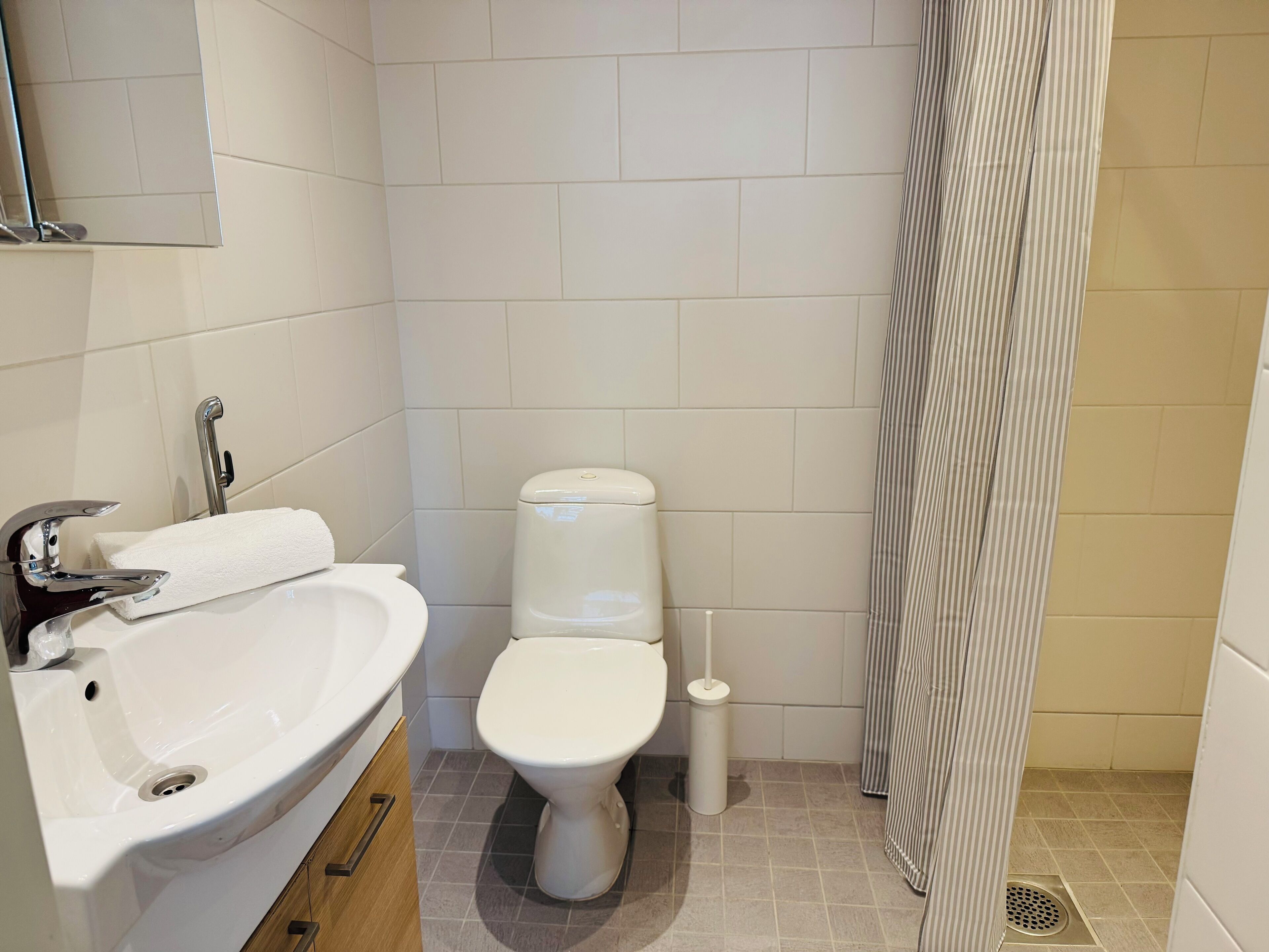 Een badkamer met een wit wastafel, toilet en douchegordijn.