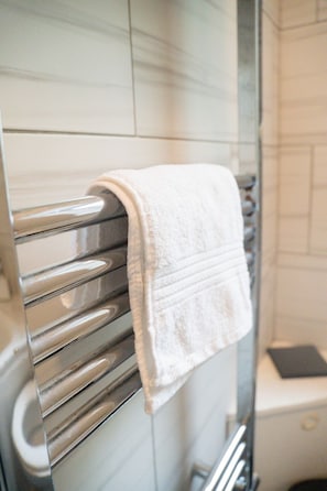 Une salle de bain comprenant un porte-serviettes avec une serviette blanche, un espace douche et des toilettes.